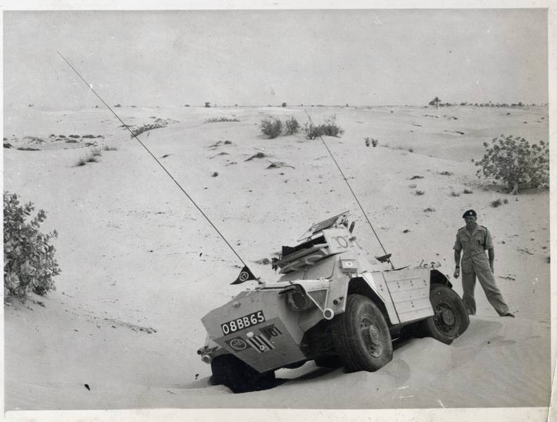 Sgt Jordan standing next to his vehicle stuck in the desert sand